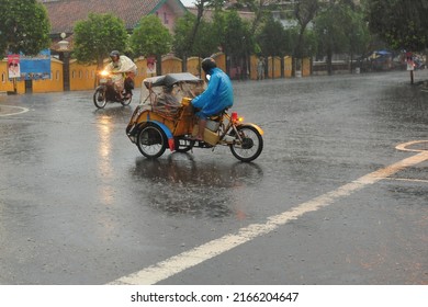 Kebumen, Indonesia - June, 2014: People Drive Under The Rain Near Kebumen Square During The Monsoon In June, 2014.