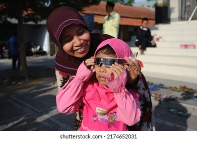Kebumen, Indonesia - March, 2016: Children observe the solar eclipse through eclipse glasses in front of the Great Mosque of Karanganyar, Kebumen. - Shutterstock ID 2174652031
