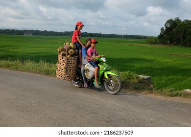 Kebumen, Indonesia - May, 2017: A man rides his daughters while carrying a coconut on a motorbike in Sugihwaras, Kebumen.