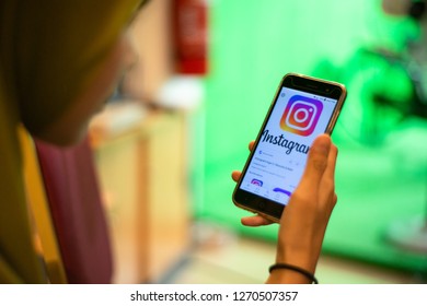 Kedah,Malaysia - 28-12-2018 : Asian Girl With Hijab Scrolling Mobile Phone And Enjoying Social Media While Waiting Someone.