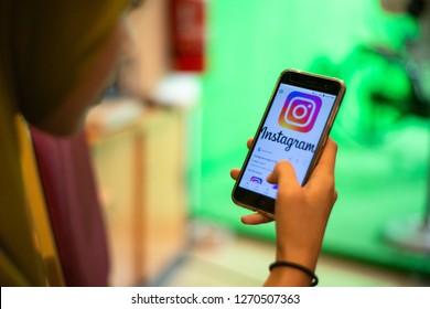 Kedah,Malaysia - 28-12-2018 : Asian Girl With Hijab Scrolling Mobile Phone And Enjoying Social Media While Waiting Someone.