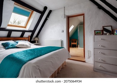 Kedington, Suffolk - November 19 2019: Bedroom in very old traditional british cottage with an abundance of exposed timbers and doorway leading to ensuite shower room. White painted walls.