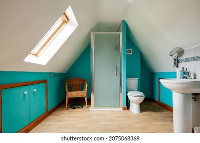 Kedington, Suffolk - November 19 2019: Shower Room With Steeply Sloping Ceiling Simply Decorated With White And Green Painted Walls, Shower Cubicle, Toilet With Seat Down And Pedestal Wash Handbasin