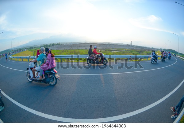 KEDIRI, INDONESIA - APRIL 11, 2021: Some\
people with their vehicle are driving in the middle of road in\
Kediri New Airport,\
Indonesia.