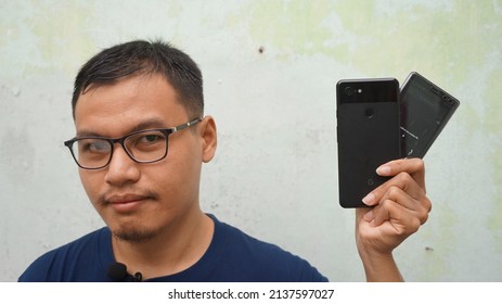 KEDIRI, INDONESIA - MARCH 7TH, 2022 - There Is A Man Whos Is Holding A Two Smartphone On Hand