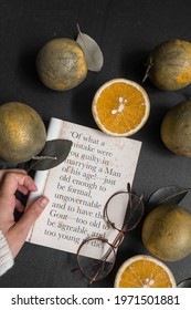 Kediri, Indonesia - May 2021: A Girl Holding A Page Of Book  From ‘Lady Susan By Jane Austen’ With Sunglasses And Slices Of Orange