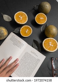 Kediri, Indonesia - May 2021: A Girl Holding A Page Of Book  From ‘Lady Susan By Jane Austen’ With Sunglasses And Slices Of Orange