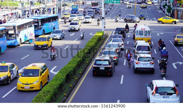 Keelung/Taiwan 11.10.2019\
bright yellow taxi on\
the streets of an asian city. urban street view of taiwan city.\
road traffic on asian streets, road marking. cars taxi mopeds buses\
on the street