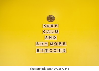 Keep calm and buy more Bitcoin, funny sign about cryptocurrency with wooden blocks on yellow background. Bitcoin price rise concept