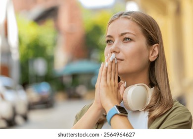 Keep calm down, relax. Teenager girl meditating, breathes deeply with hands clasped, praying eyes opened, concentrated thoughts, peaceful mind outdoors. Young woman taking a break in urban city street