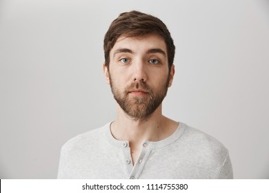 Keep Calm And Pretend Nothing Happened. Portrait Of Calm Serious Mature Male With Beard Standing With No Emotions Over Gray Background, Staring At Camera Without Interest. Man Careless About Anything