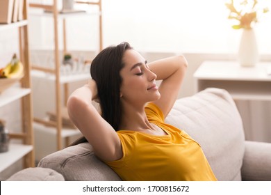 Keep calm and stay home. Peaceful young woman relaxing on sofa in living room - Powered by Shutterstock