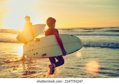 Keep calm and surf on. Shot of two young brothers carrying their surfboards while wading into the ocean. - Powered by Shutterstock