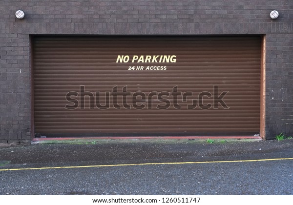 Keep clear no parking 24 access\
required sign at business entrance roller shutter\
doors