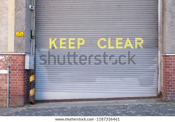 Keep\
clear sign on roller shutter door large yellow text\
