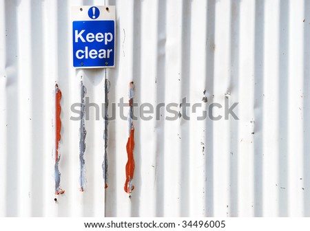 Keep clear sign screwed onto corrugated fence