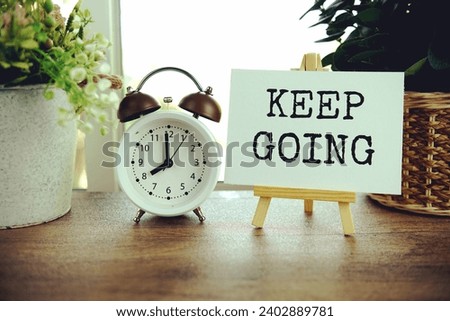 Keep going text message on paper card with wooden easel on wooden table background, inspiration motivation concept