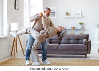 Sigue moviéndose. Romántica pareja de ancianos de familia esposa y esposo bailando juntos música en la sala de estar, sonriendo riente jubilado y mujer divirtiéndose, disfrutando del tiempo libre juntos en casa