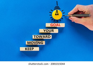 Keep moving toward your goal symbol. Wooden blocks with words Keep moving toward your goal. Light bulb icon. Businessman hand, pen. Blue background, copy space. Business, your goal concept.