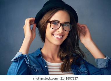 Keep On Smiling. Portrait Of A Quirky Young Woman Smiling Against A Gray Background In Studio.