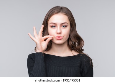 Keep the secret - keep quiet. Young woman zips her mouth shut, promises to keep secret. Silence and secret concept - Shutterstock ID 1931495351