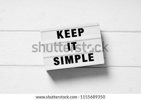keep it simple text on lightbox sign, minimal flat lay design on white wooden background, simplicity or minimalism concept