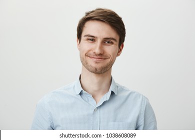 Keep Talking But I Do Not Care. Portrait Of Polite Bothered Attractive Office Worker In Casual Shirt Pulling Fake Smile And Trying To Look Friendly While Standing Over Gray Background, Being Annoyed