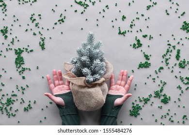 Keep Using Your Fake Faux Xmas Tree As Long As Possible. Alternative Green Eco Friendly Christmas Concept. Hands Show Plastic Tree Wrapped In Burlap Mesh With Plastic Particles On Brown Craft Paper.