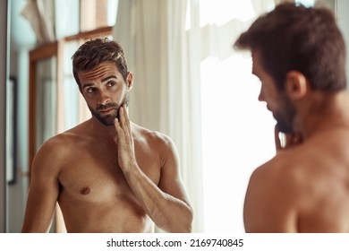 Keeping a close eye on any signs of aging. Shot of a shirtless man checking out his skin in the bathroom mirror.