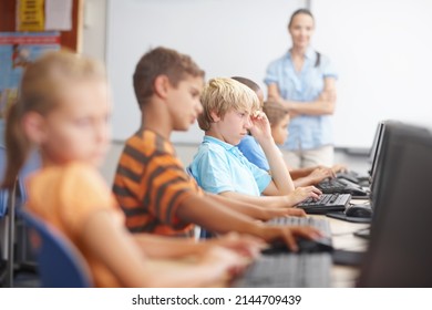 Keeping a close eye on her class. A group of young kids working hard in computer class. - Powered by Shutterstock