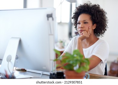 Keeping up to date with online developments. Beautiful creative professional looking intently at her pc in a bright open plan office space. - Shutterstock ID 2129307851