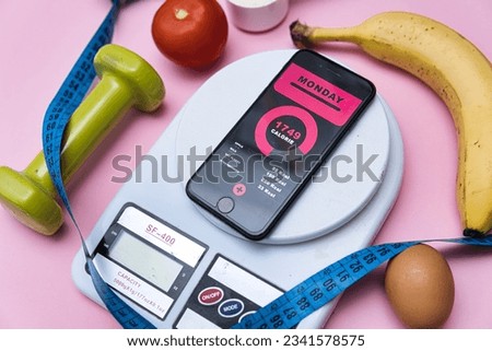 Keeping fit and getting in shape through exercise, healthy diet and calorie counting. Flat lay photo showing calorie counting app, healthy food and kitchen scale