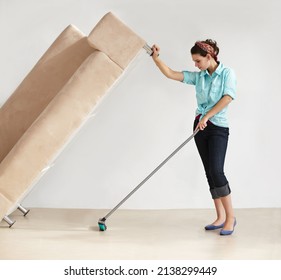 Keeping The House Clean Takes Super Strength. Strong Young Woman Lifting A Couch And Washing The Floor Beneath It.