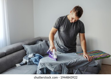 Keeping The House Tidy, Ironing. A Male Person Irons A Shirt On A Colorful Ironing Board In The Living Room In The Morning. Keep Home Clean, Happy To Help