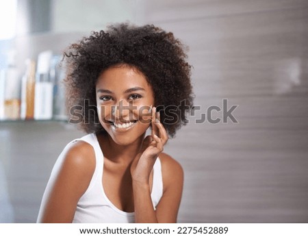 Keeping my skin totally smooth. An attractive young woman applying cream to her face.
