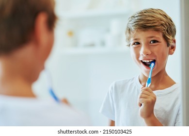 Keeping my teeth strong. Shot of a cheerful young boy looking at his reflection in a mirror while brushing his teeth in the bathroom at home during the day. - Powered by Shutterstock