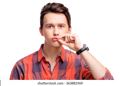 Keeping secret. Don't talk. Portrait of young man in plaid shirt closing his mouth with  hand. Isolated on white.