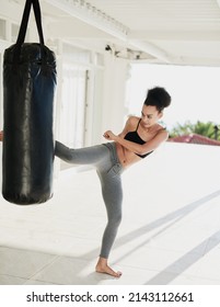 Keeping In Tip Top Shape. Shot Of A Sporty Young Woman Working Out With A Punching Bag Outside.