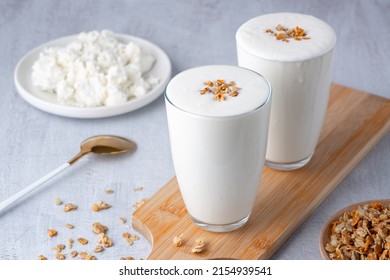 Kefir, buttermilk or yogurt, cottage cheese with granola. Yogurt in glass on light background. Probiotic cold fermented dairy drink. Gut health, fermented products, healthy gut flora concept.