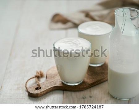 Kefir, buttermilk or yogurt with probiotics. Yogurt in glass on white wooden background. Probiotic cold fermented dairy drink. Gut health, fermented products, healthy gut flora concept. Copy space