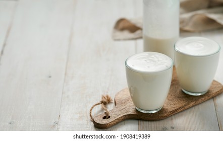 Kefir, buttermilk or yogurt with probiotics.Yogurt in glass on white wooden background.Probiotic cold fermented dairy drink.Gut health, fermented products, healthy gut flora concept. Copy space.Banner