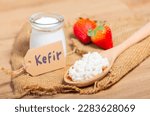 Kefir grains in wooden spoon in front of cups of Kefir Yogurt Parfaits. Kefir is one of the best health foods available providing powerful probiotics.