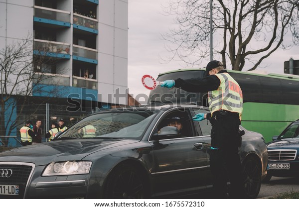 Kehl, Germany - Mar 16, 2020: An officer of\
the Federal Police checks paper at the border crossing in Kehl from\
France Strasbourg during crisis measures in the fight against the\
novel coronavirus.