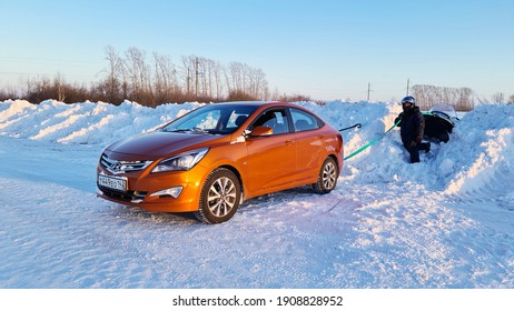 Kemerovo, Kemerovo Region, Russia - 02.02.2021 An Orange Sedan Pulls Out A Snowmobile Stuck In The Snow