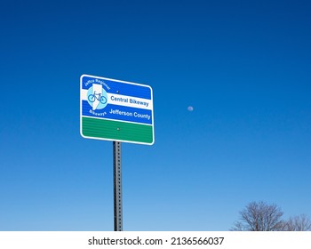 Ken Caryl, Colorado, USA, March 10, 2022, Jefferson County bikeway sign with the moon in the background blue sky
