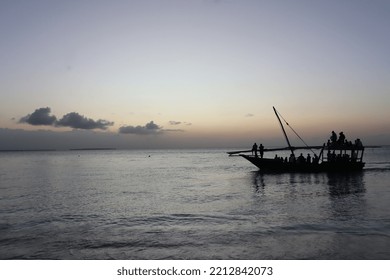 Kendwa, Zanzibar Island, Tanzania Dhow Boat Sailing Against The Setting Sun And Cloudy Sky.