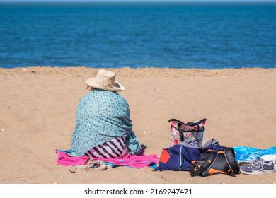 Kent, England - 14 June, 2022 - A senior woman enjoying sunshine on the sandy beach at Botany Bay in the seaside town of Broadstairs