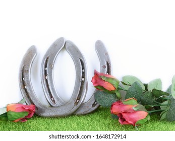 Kentucky Derby Image Of A Pair Of Horseshoes And Red Roses On Green Grass With White Background. Copy Space