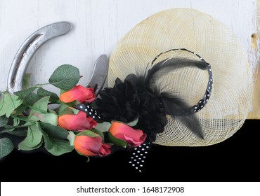 Kentucky Derby Photo Of A Fascinator Hot With Red Roses And A Horseshoe. On A Black Table With Rustic Wooden Wall.