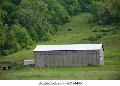 Kentucky Tobacco Barn - A Tobacco Barn On The Side Of A Grassy Ridge In Spring With The Slats Closed.